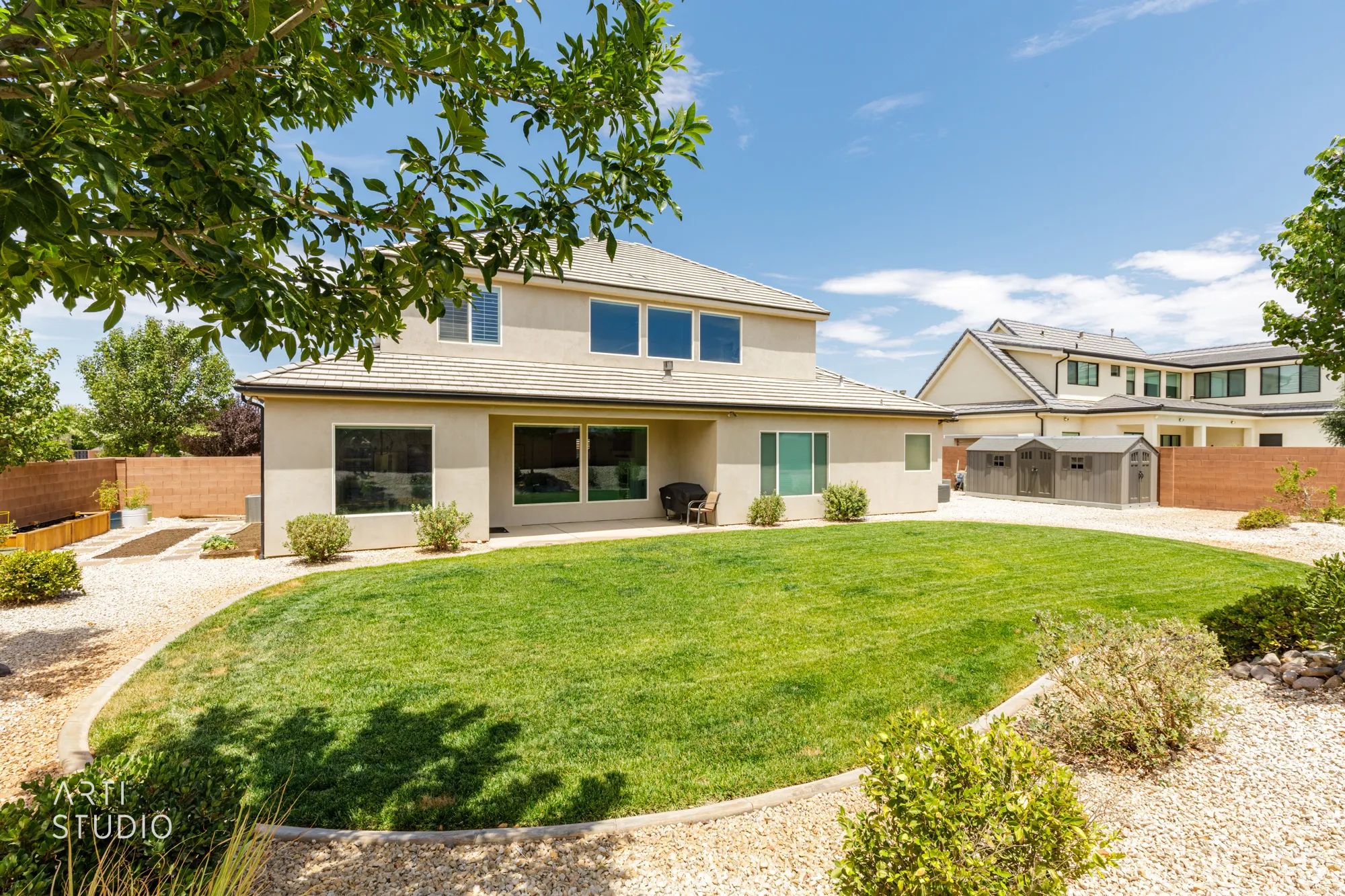 Expansive rear yard featuring a curved lawn, gravel landscaping, and mature trees