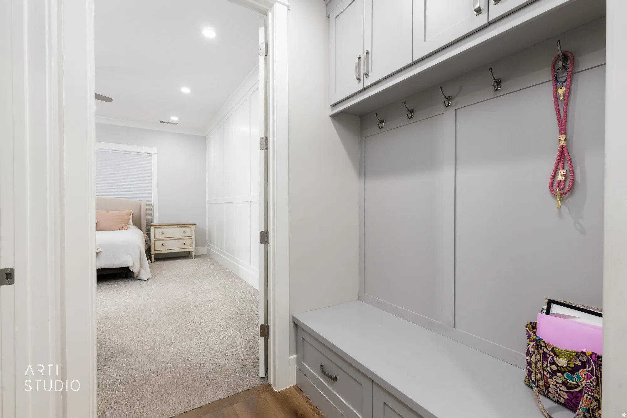 Built-in mudroom bench with integrated storage drawers, upper cabinetry, and wall-mounted hooks