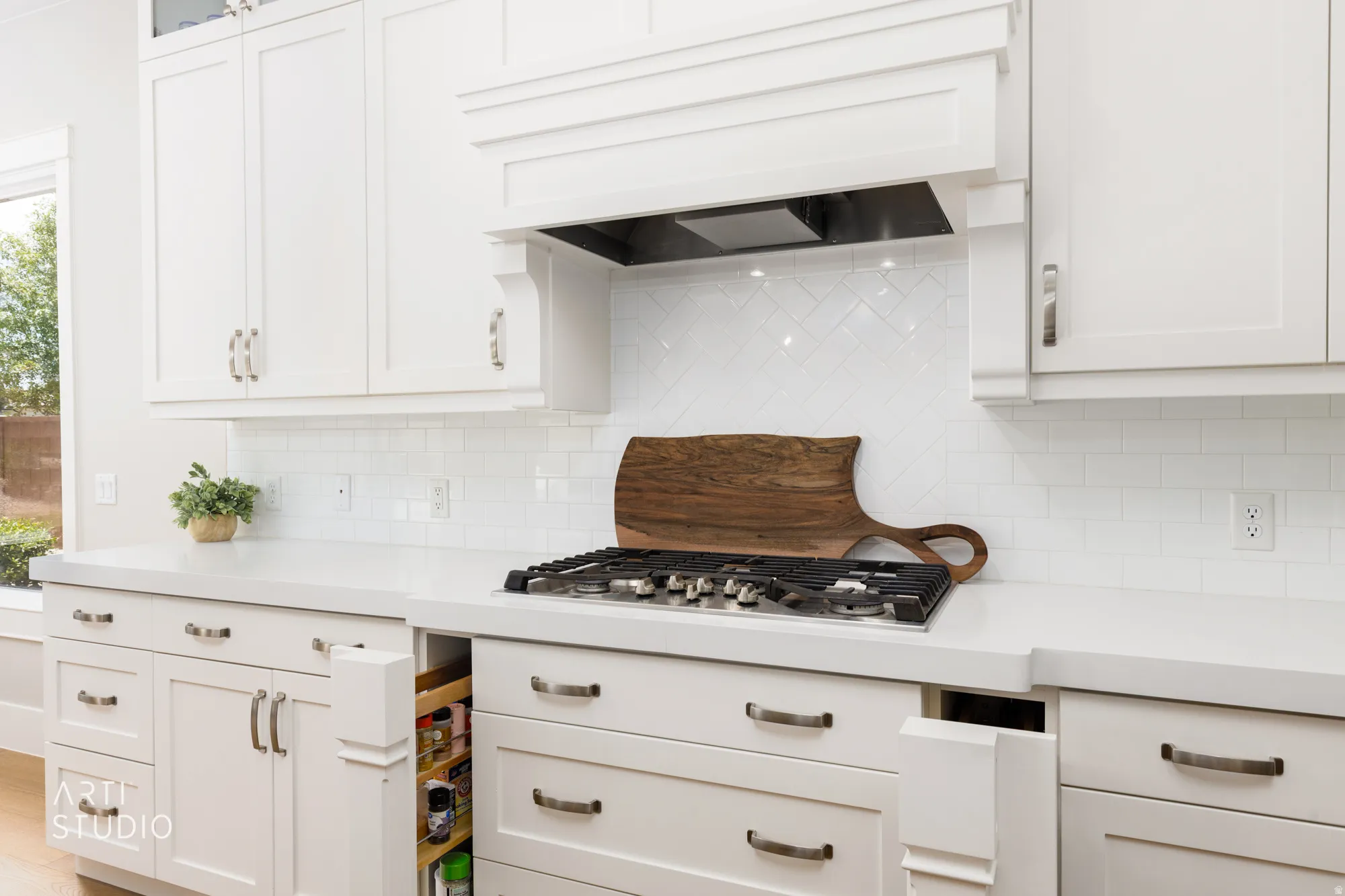 White cabinetry with brushed nickel hardware, light-toned countertops, subway tile backsplash, and built-in gas range
