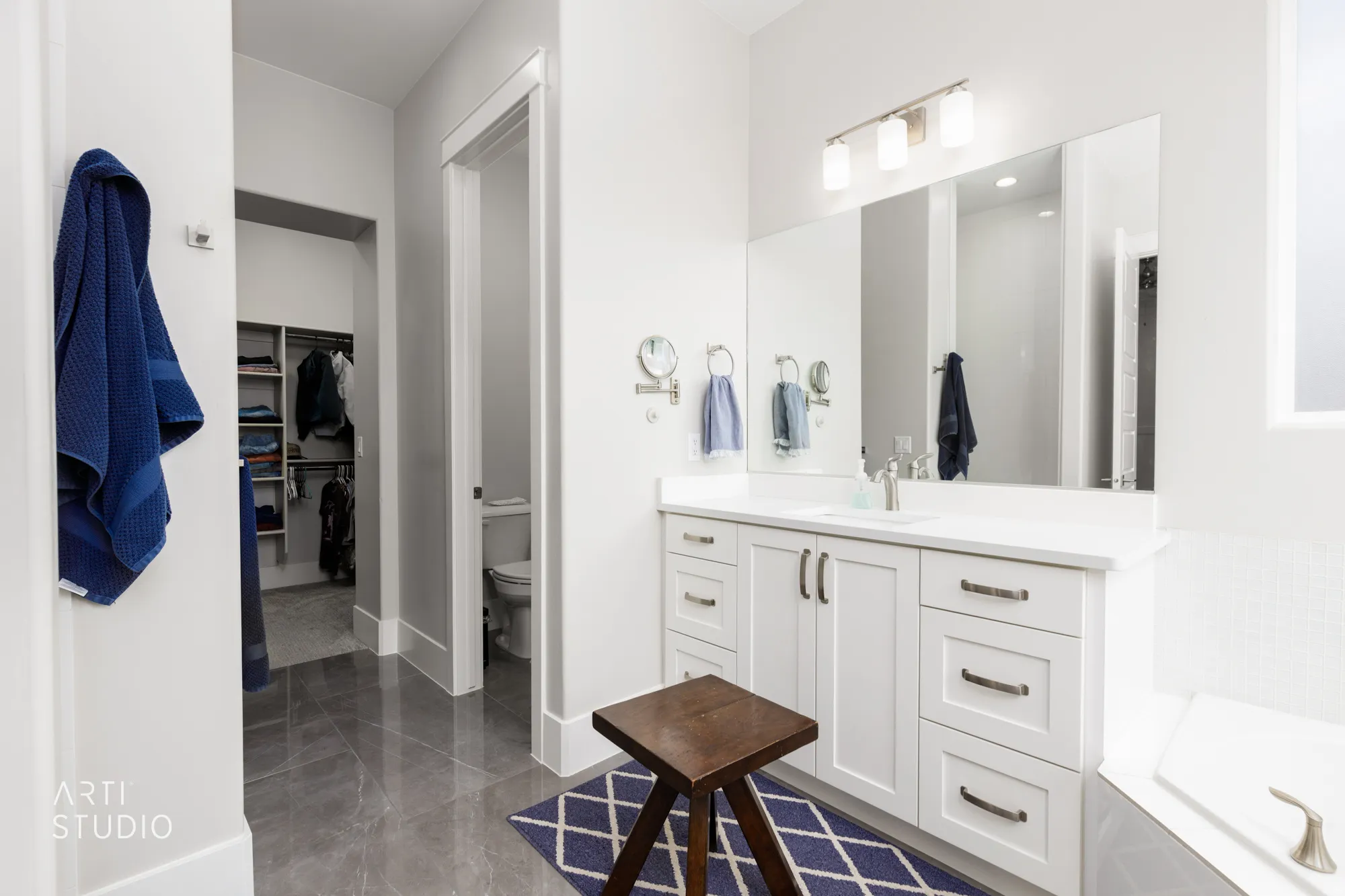 Bathroom vanity with white cabinetry, a single undermount sink, and a large wall-mounted mirror