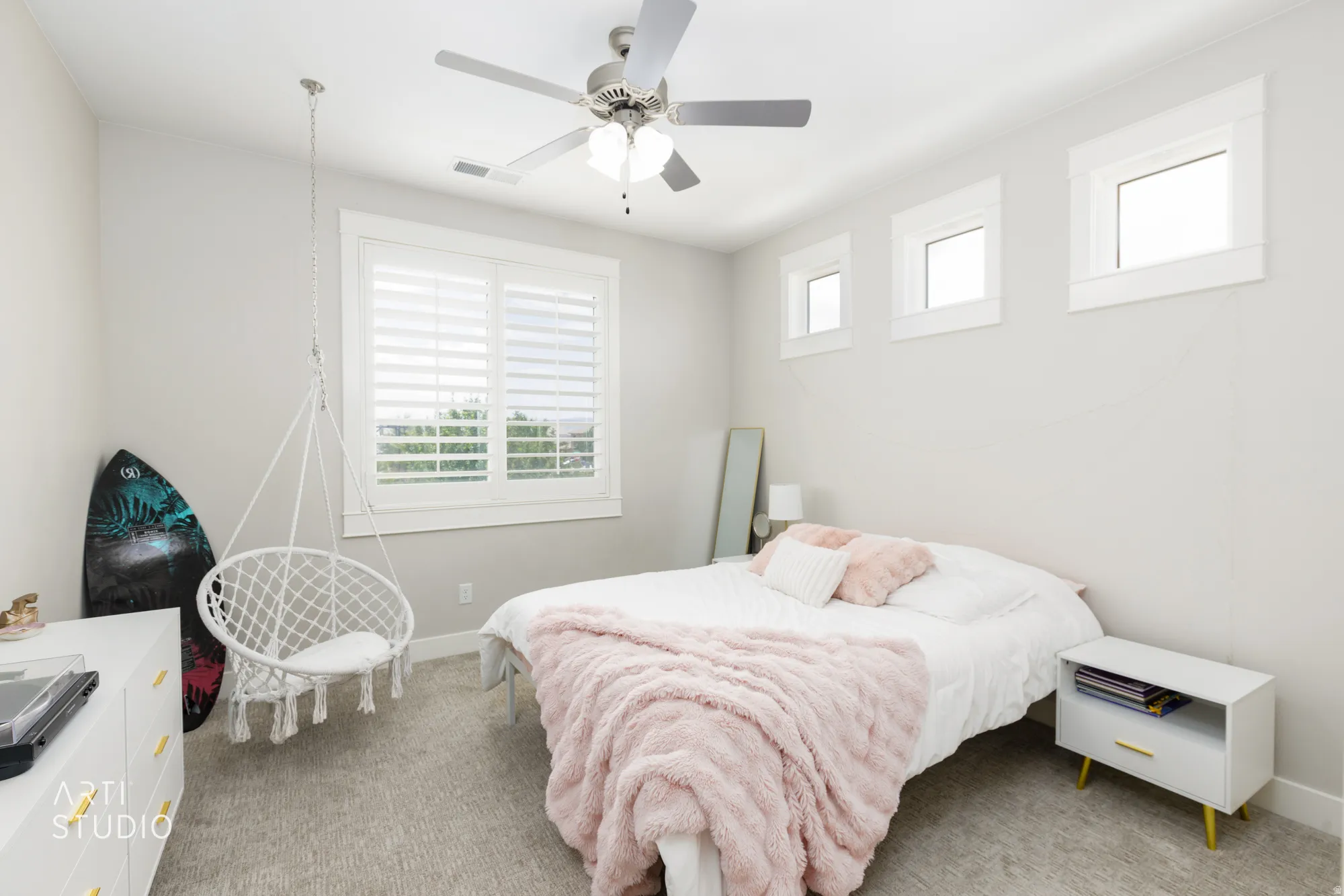 Well-lit room featuring multiple windows with white trim, a ceiling fan, and carpeted flooring