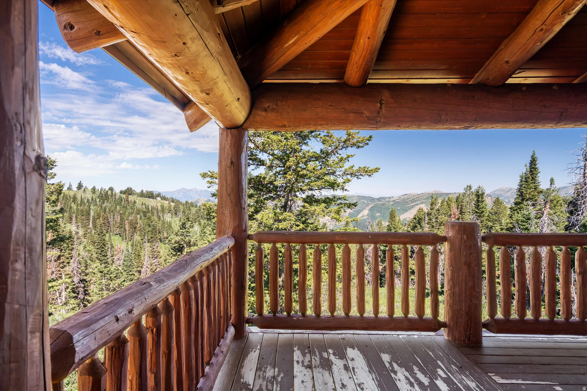 Expansive wooden deck featuring substantial log construction with a slatted wood railing