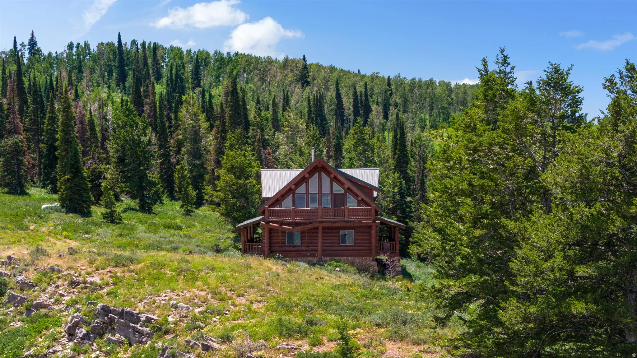 Log cabin residence featuring a gabled roofline and a second-story balcony