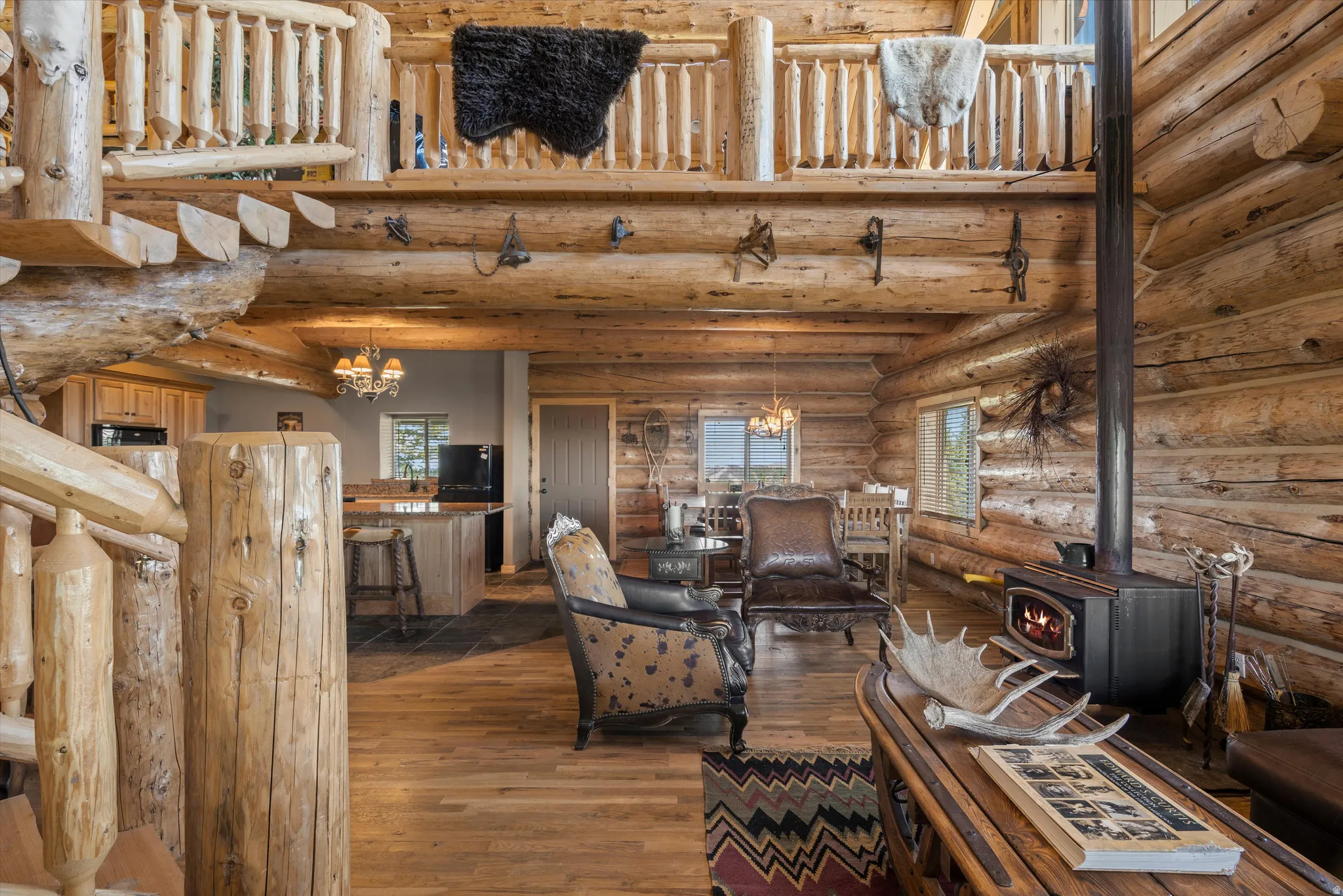 Expansive great room featuring a wood-burning stove, rich wood-finish flooring, and exposed log construction throughout