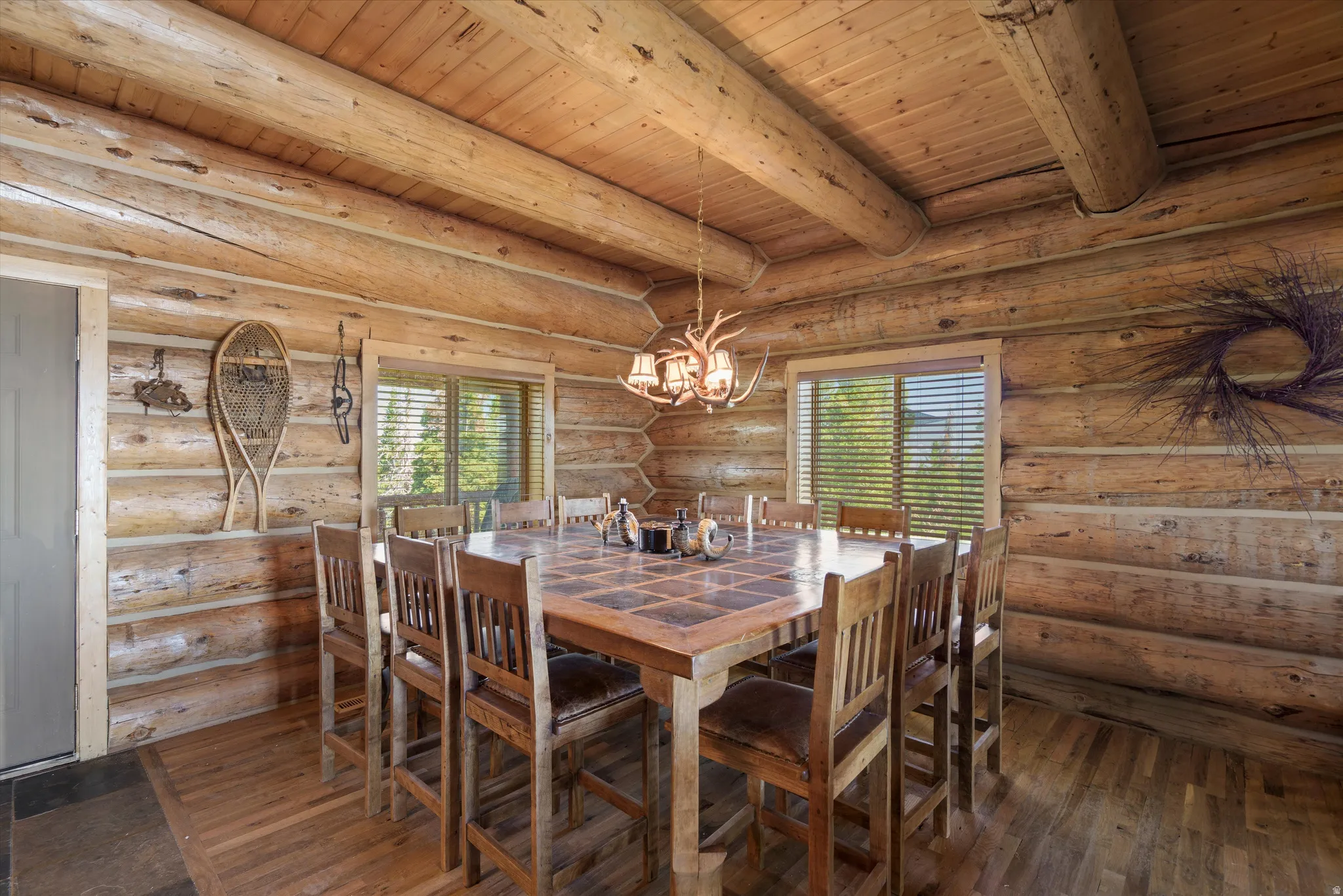 Log cabin interior featuring exposed log walls, a wood-finish ceiling with exposed beams, and wood-finish flooring