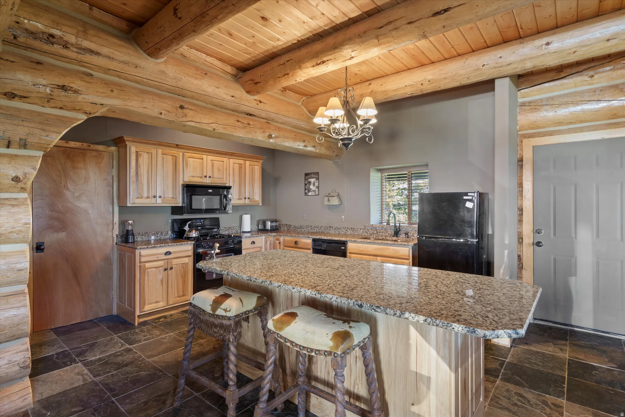 Kitchen featuring wood cabinetry, black appliances, and a granite-finish island