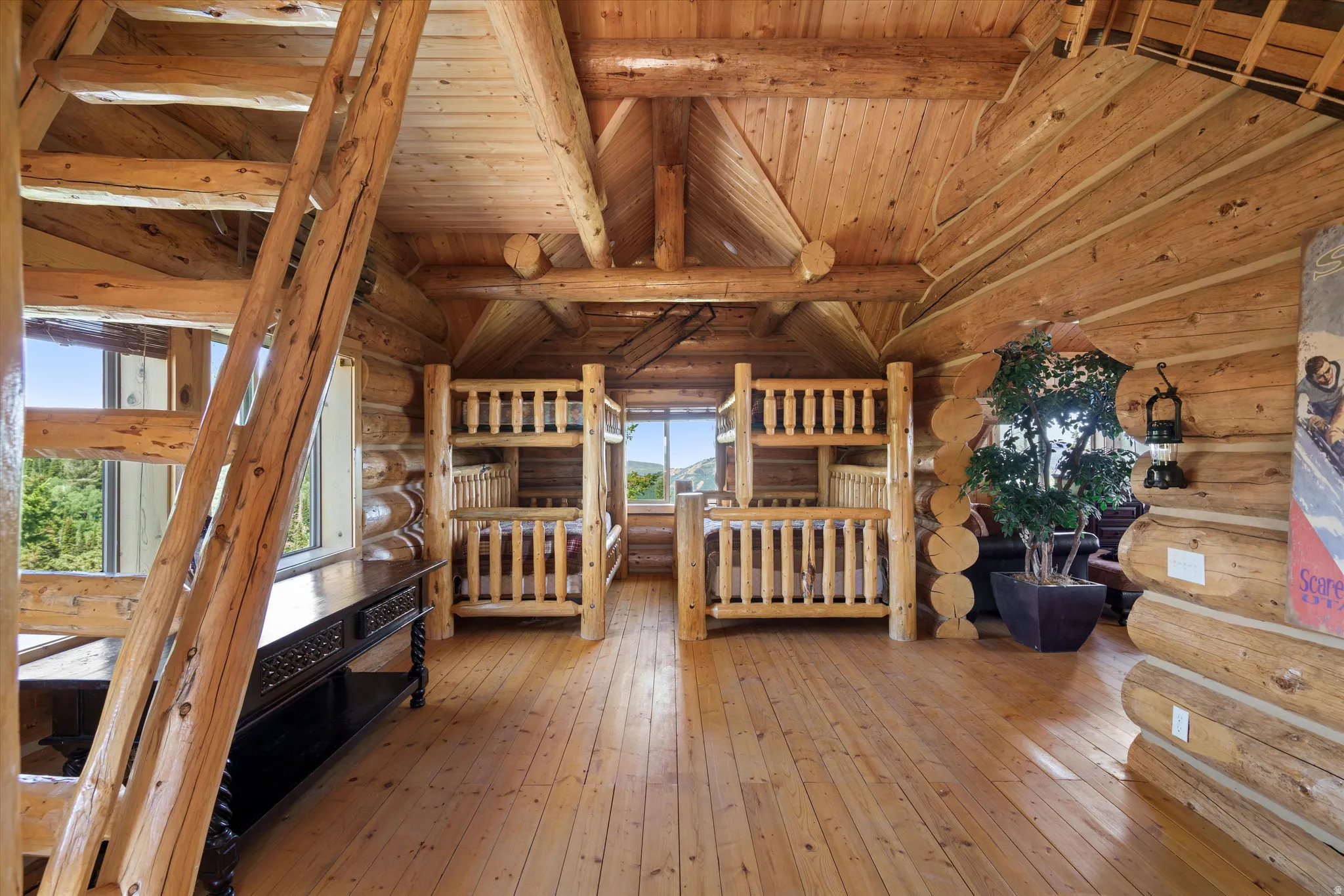 Spacious log-cabin interior featuring exposed log walls, natural wood flooring, and a prominent wood staircase