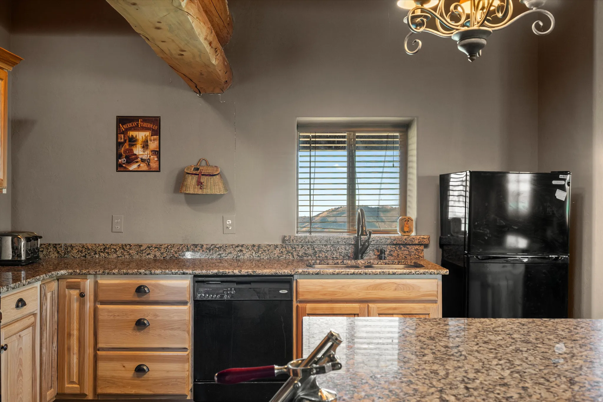 Kitchen featuring natural wood cabinetry, speckled countertops, a double basin sink, and a black dishwasher