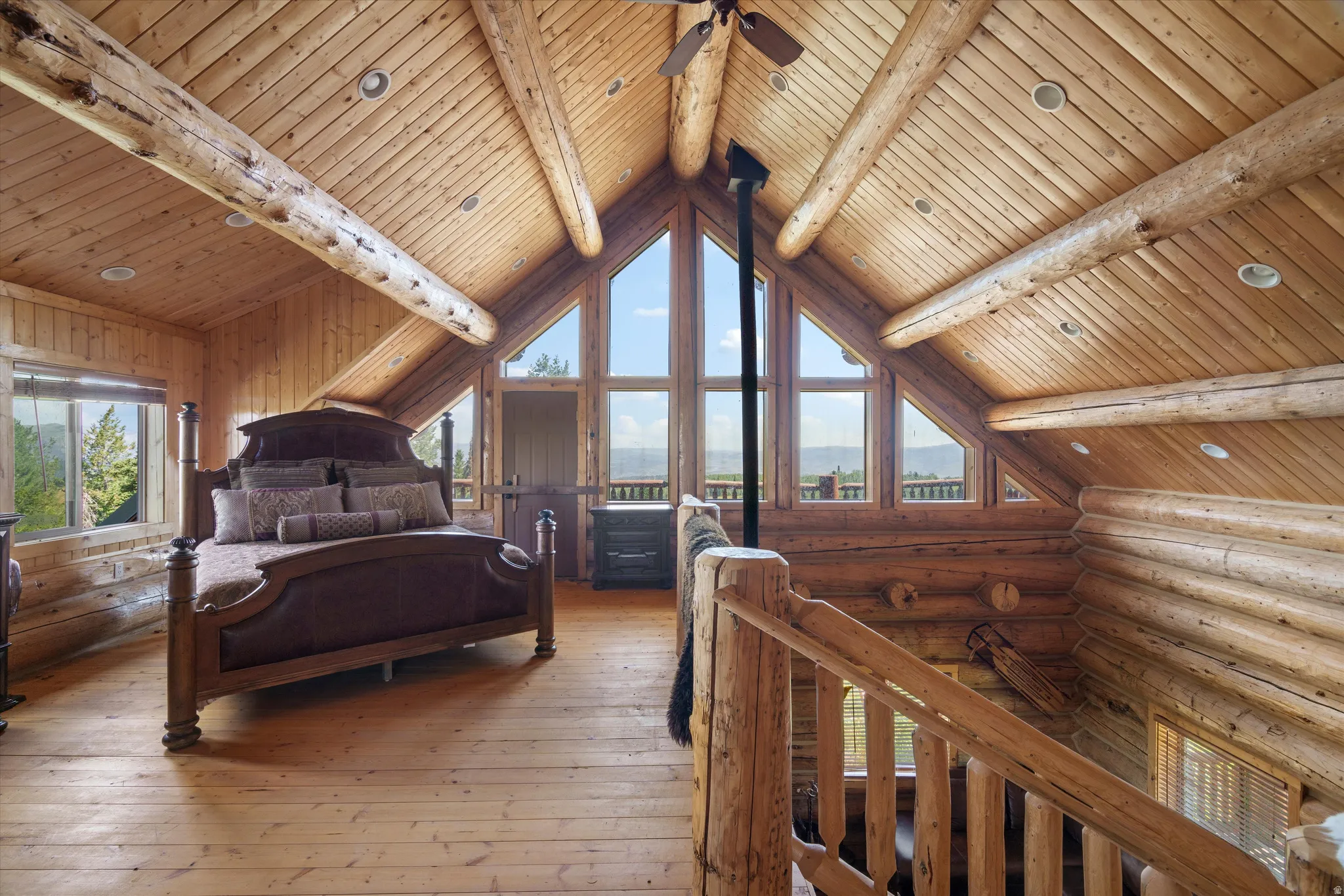 Lofted room with exposed log beams and a vaulted wood-paneled ceiling