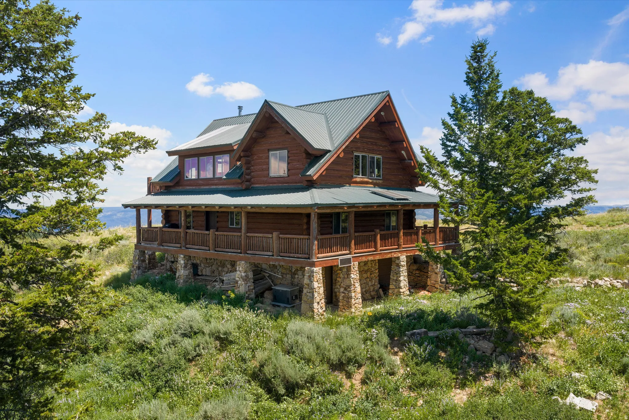 Rustic log home featuring a multi-level design and a dark green metal roof