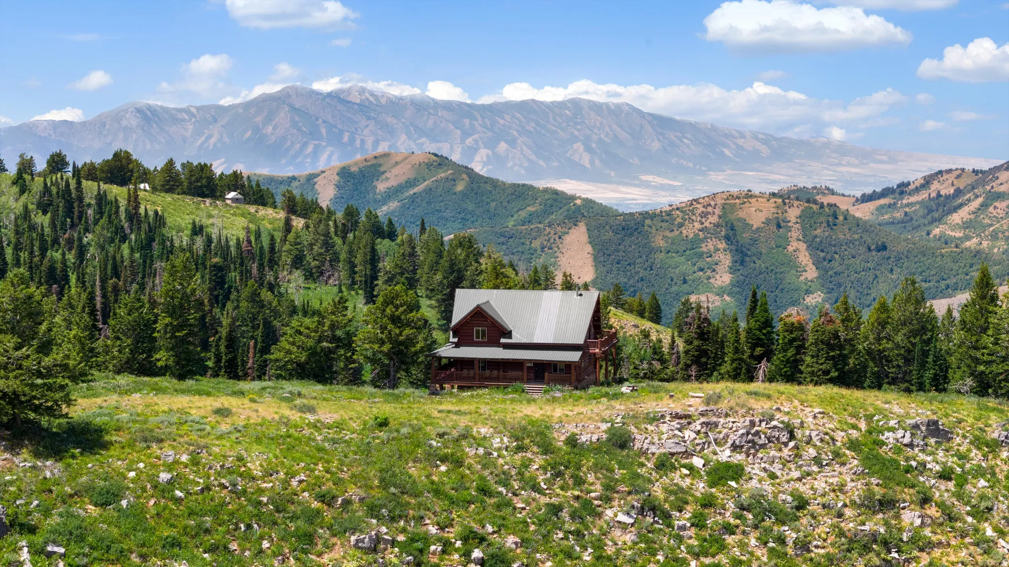 Mountain-side residence featuring a wood-sided exterior, a covered front porch, and a dark metal roof