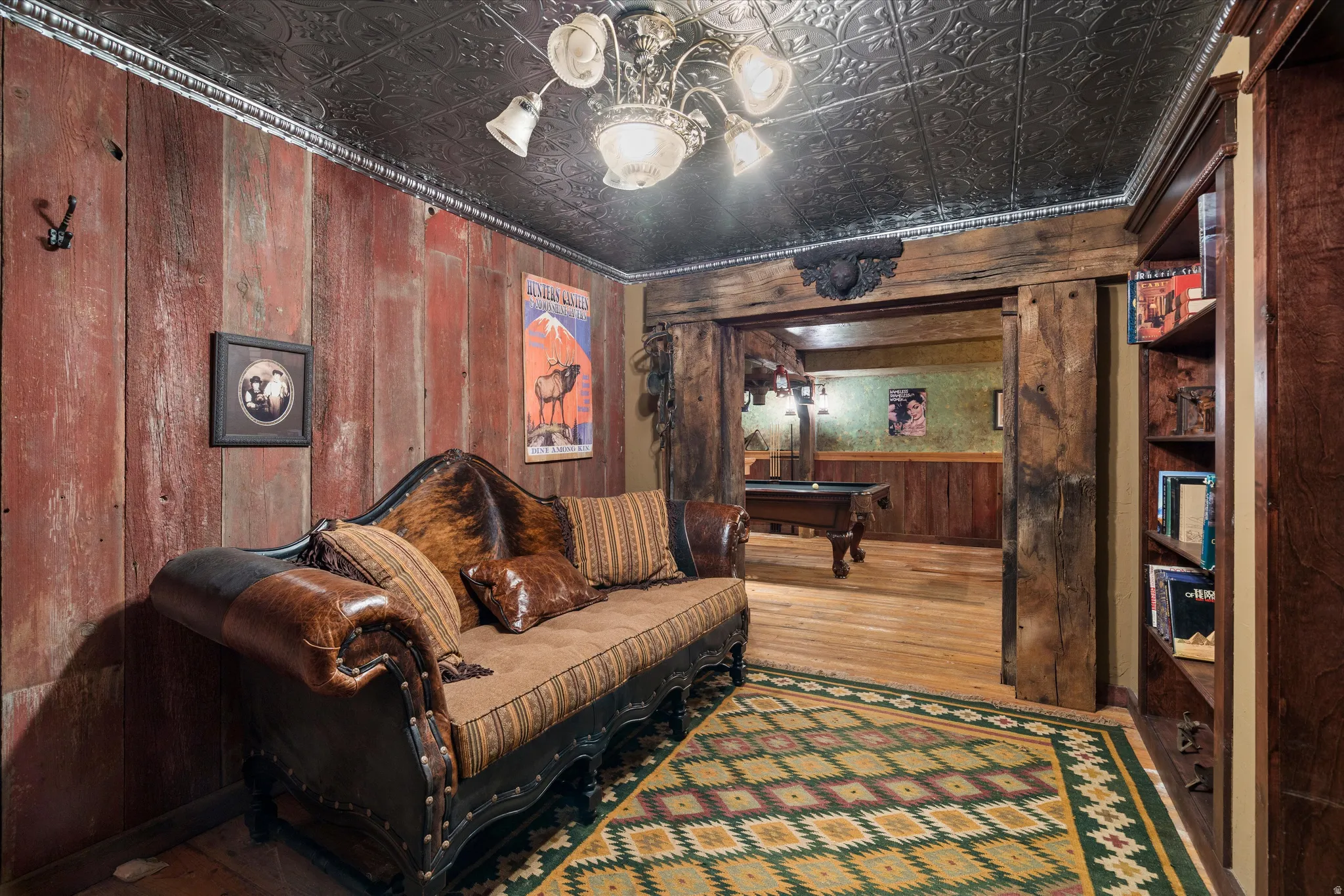 Room featuring distressed wood paneling, a dark pressed-tin ceiling, and wood-finish flooring