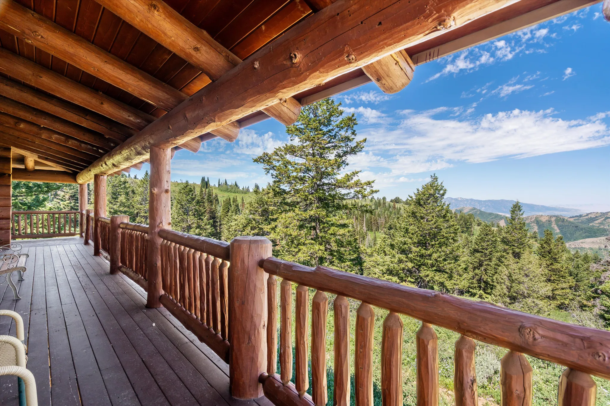 Expansive log cabin porch featuring natural wood beams, wooden railing, and a durable wood plank floor