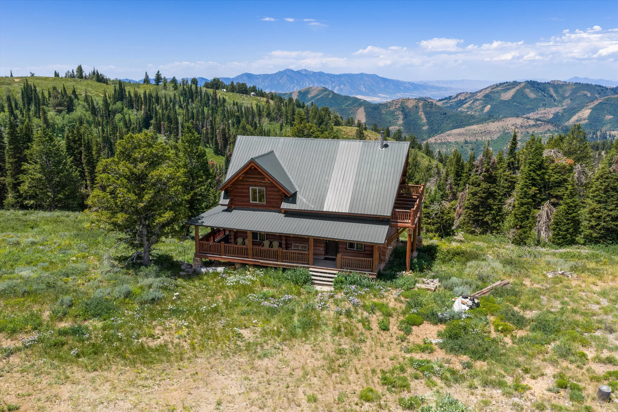Mountain log cabin featuring a metal roof, expansive wrap-around porch, and a second-story balcony
