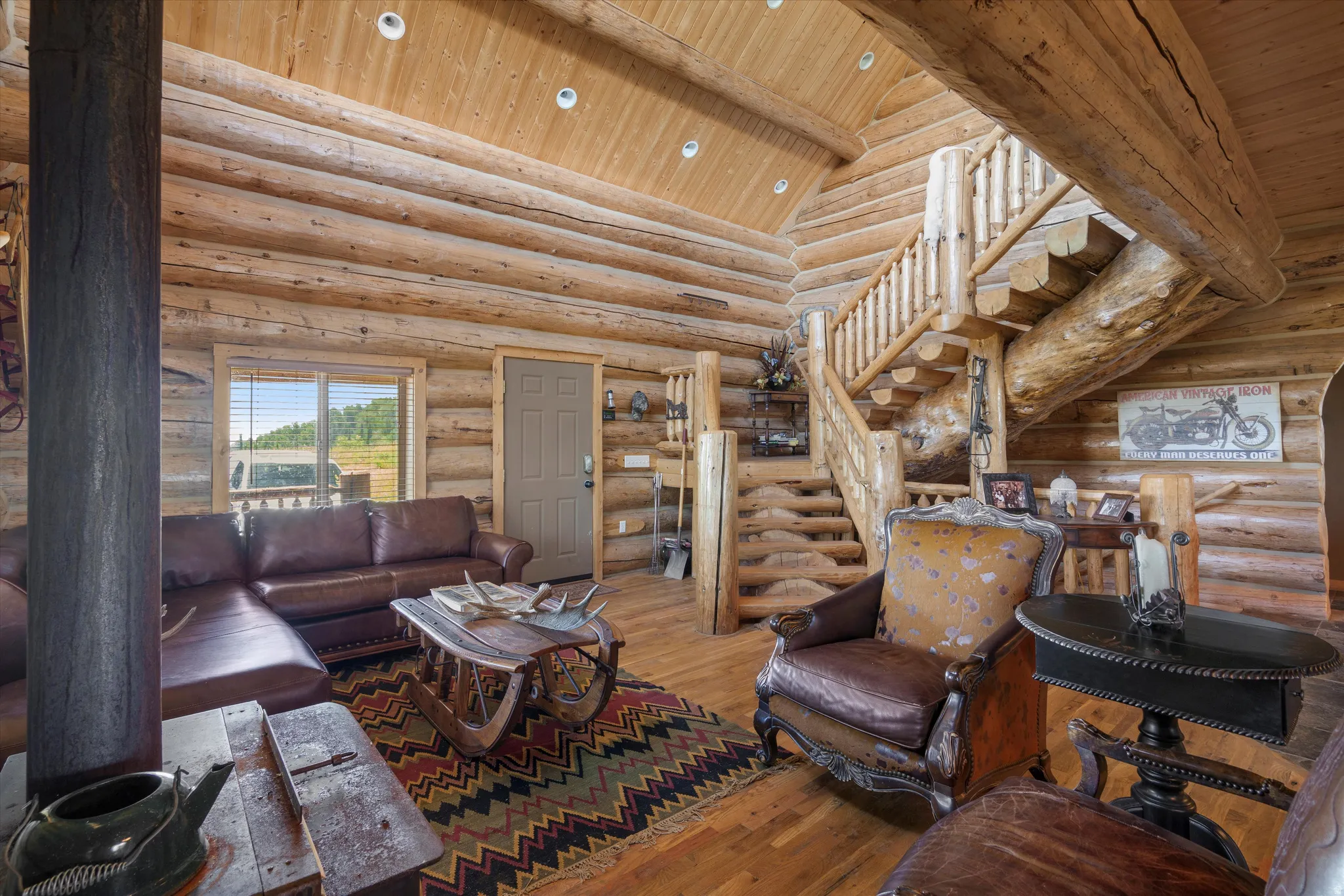 Expansive living area showcasing log construction throughout, vaulted wood-finish ceilings, and a prominent log staircase