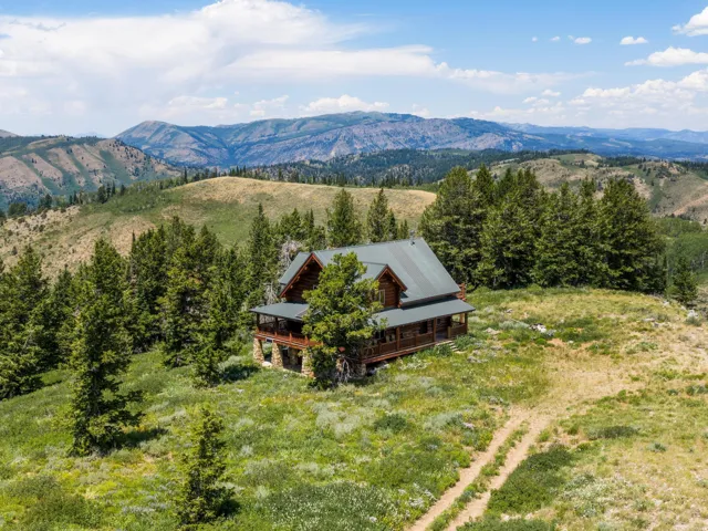 Log cabin residence set amidst a mountainous landscape with mature evergreen trees