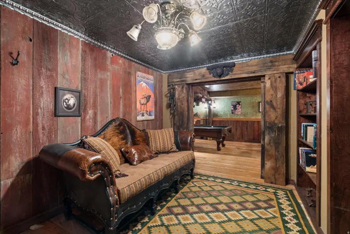 Room featuring distressed wood paneling, a dark pressed-tin ceiling, and wood-finish flooring