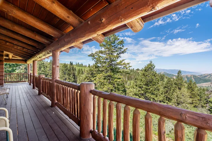 Expansive log cabin porch featuring natural wood beams, wooden railing, and a durable wood plank floor