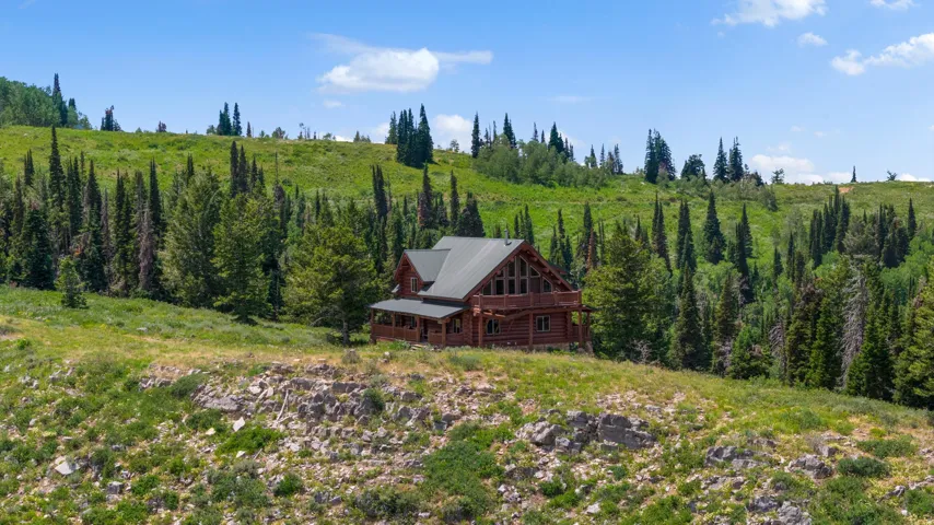 Rustic log cabin exterior with a multi-level design, featuring a covered porch and an upper-level balcony
