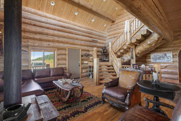 Expansive living area showcasing log construction throughout, vaulted wood-finish ceilings, and a prominent log staircase