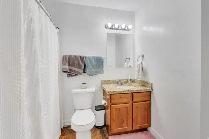 Bathroom vanity featuring a light-toned stone countertop and wood-finish cabinetry