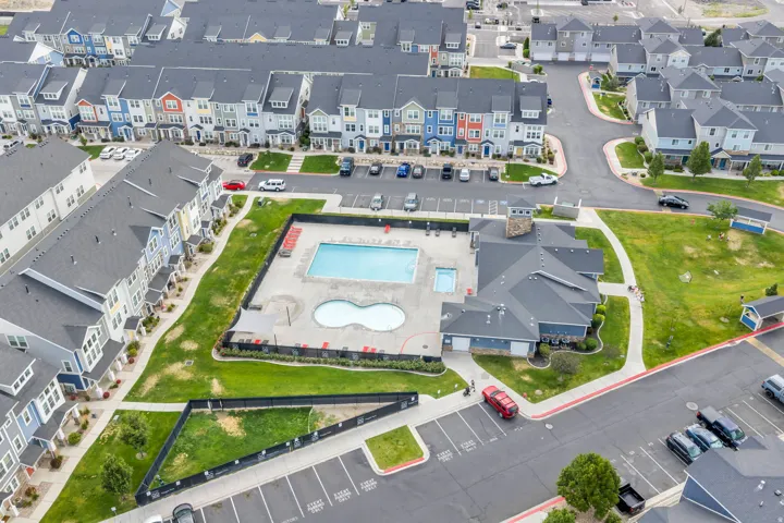 Community amenity center featuring a rectangular swimming pool, an adjacent smaller kidney-shaped pool, and a clubhouse building with a stone-clad chimney