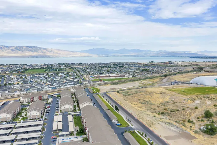 Aerial perspective showcasing a residential community with multi-story buildings, extensive paved parking, and structured covered parking