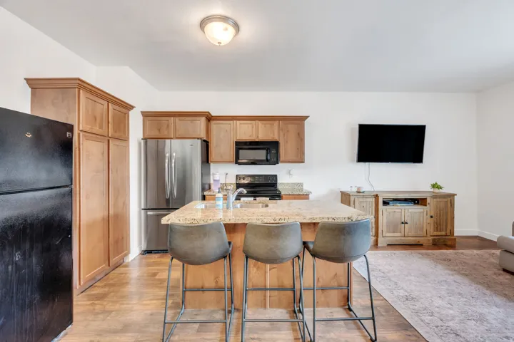 Kitchen featuring wood-finish flooring, light wood cabinetry, and a center island with a speckled countertop