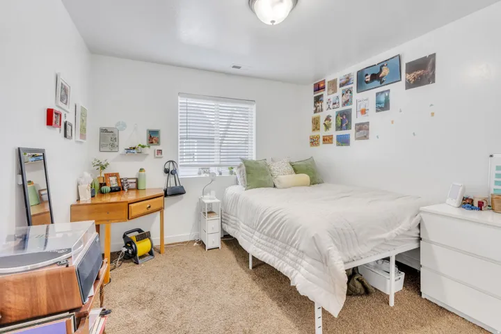 Carpeted interior room with white walls and a window featuring horizontal blinds