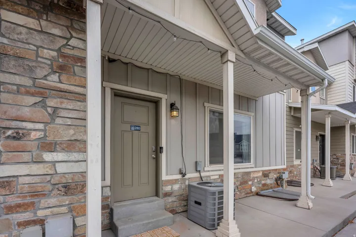 Entryway featuring stone veneer facade, a covered porch, board and batten siding, and an exterior light fixture