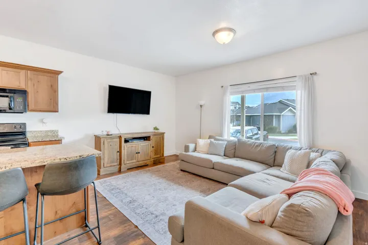 Open-concept living space featuring wood-finish flooring and a large window with sheer curtains