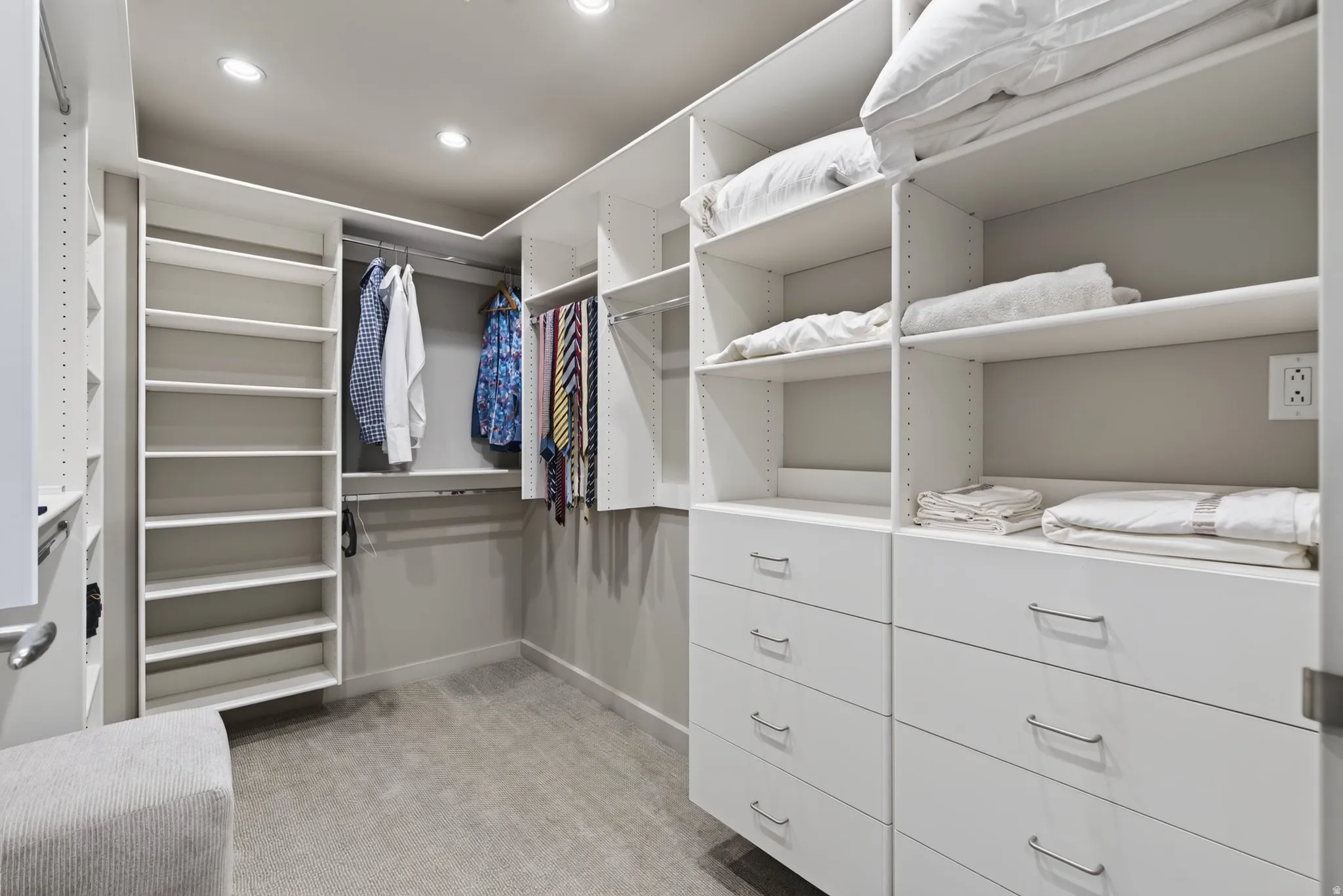 Custom white built-in closet system featuring multiple shelving units, hanging rods, and integrated drawer storage with brushed nickel hardware