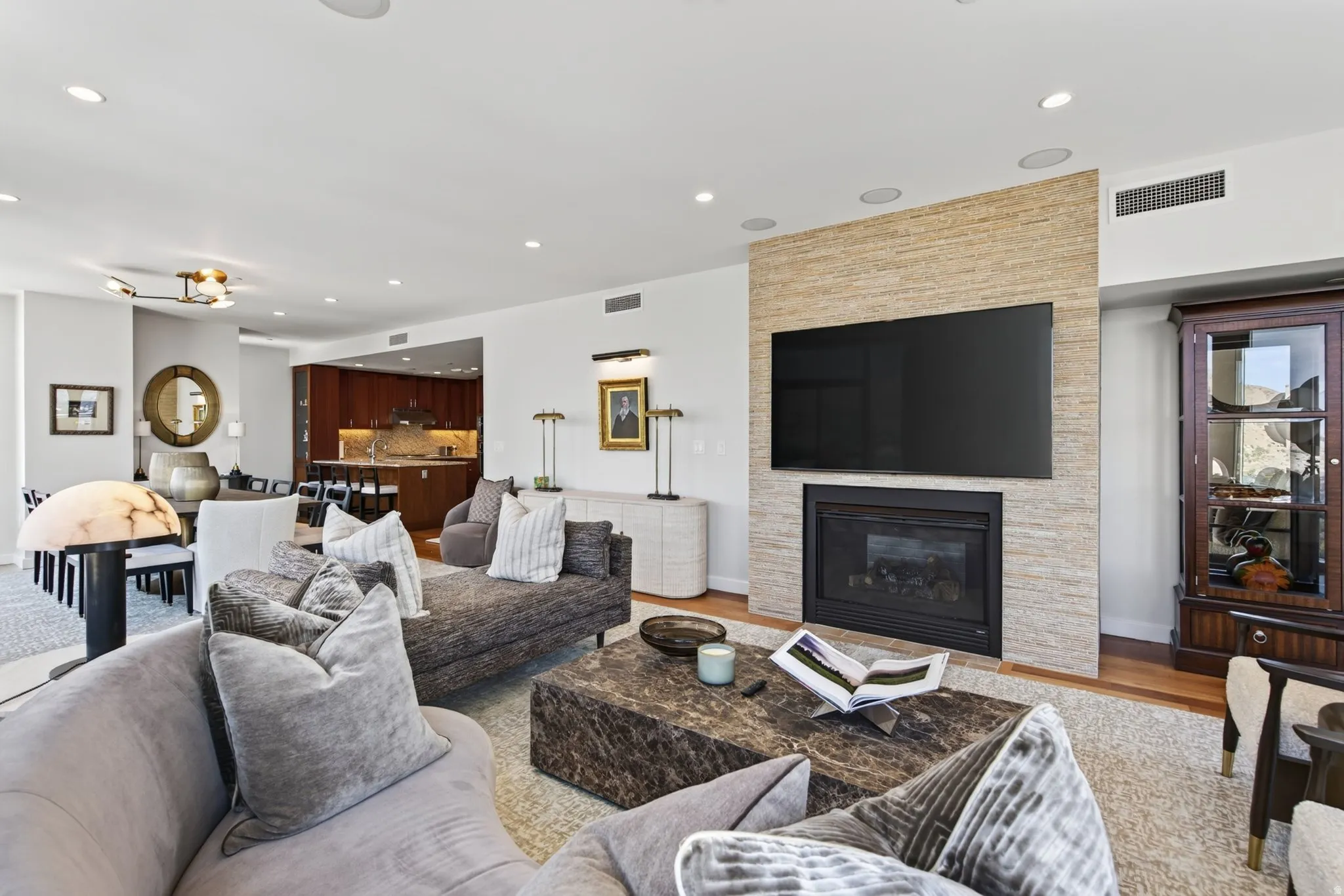 Spacious living area featuring a built-in fireplace with a textured stone surround, recessed lighting, and wood-finish flooring
