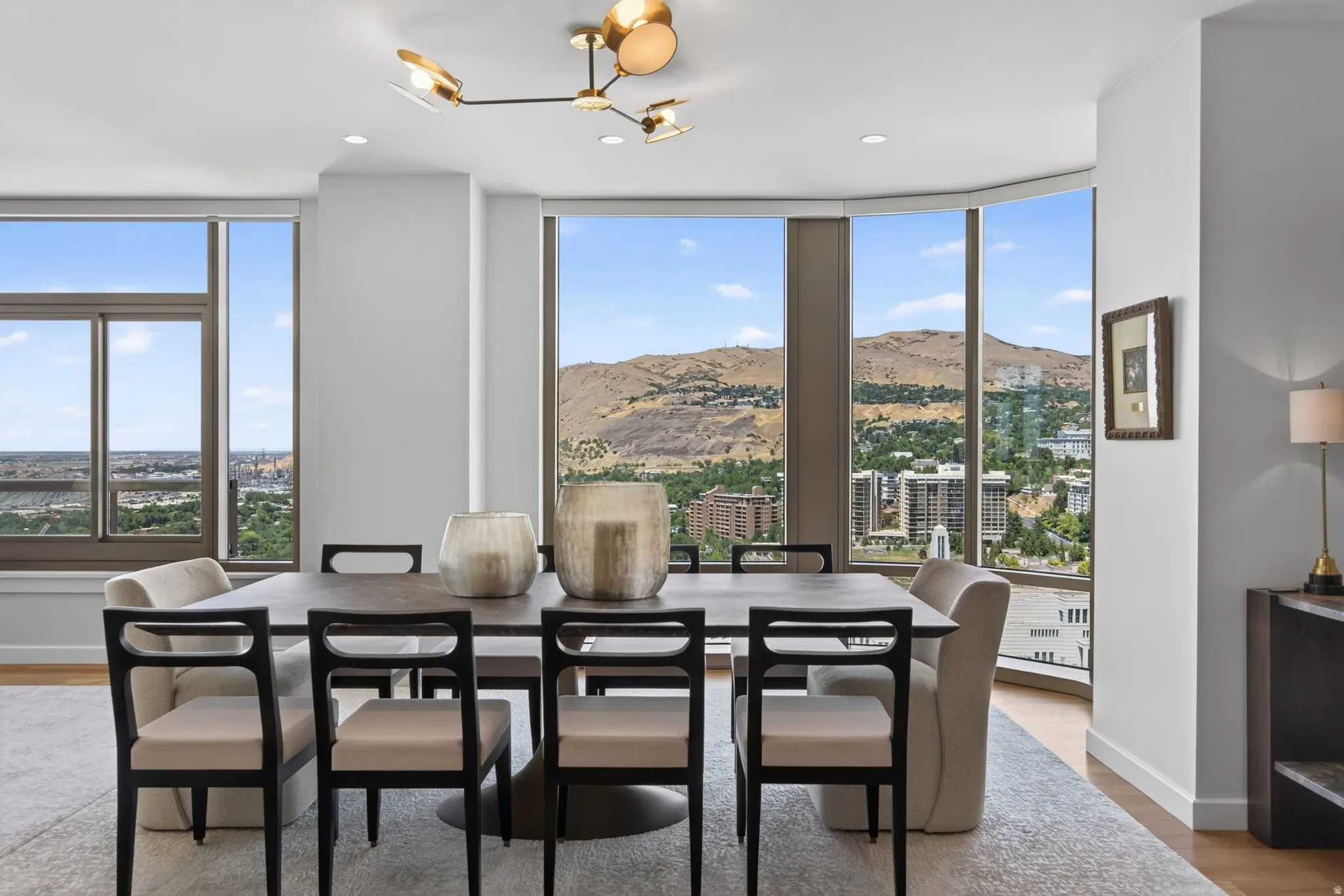 Dining area featuring floor-to-ceiling windows, a modern brass chandelier, recessed lighting, light wood-finish flooring, and a neutral area rug