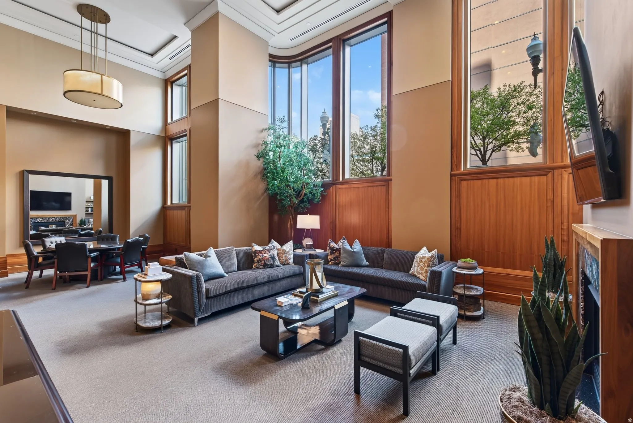 Grand living space featuring high ceilings, extensive wood paneling, and large picture windows