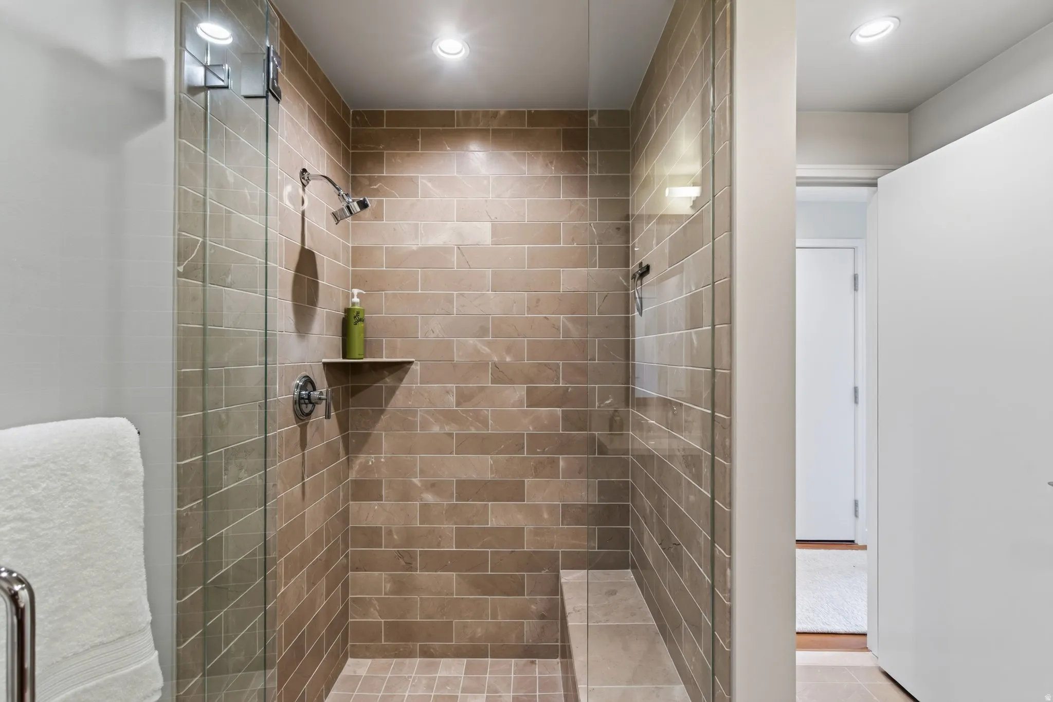 Walk-in shower featuring subway tile walls, a built-in bench, a recessed shelf, and a glass enclosure