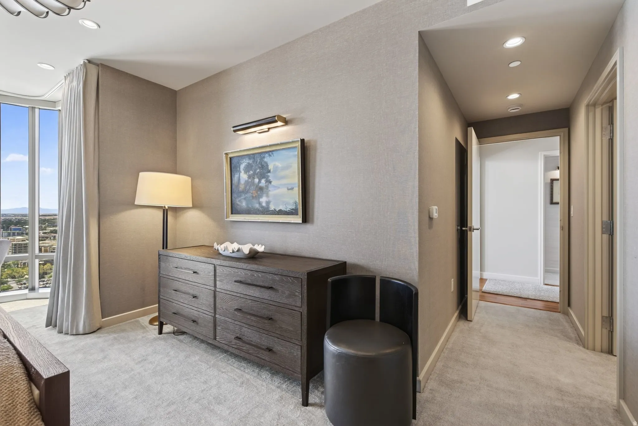 Wall-to-wall carpeting throughout this space with a full-height window featuring vertical drapes