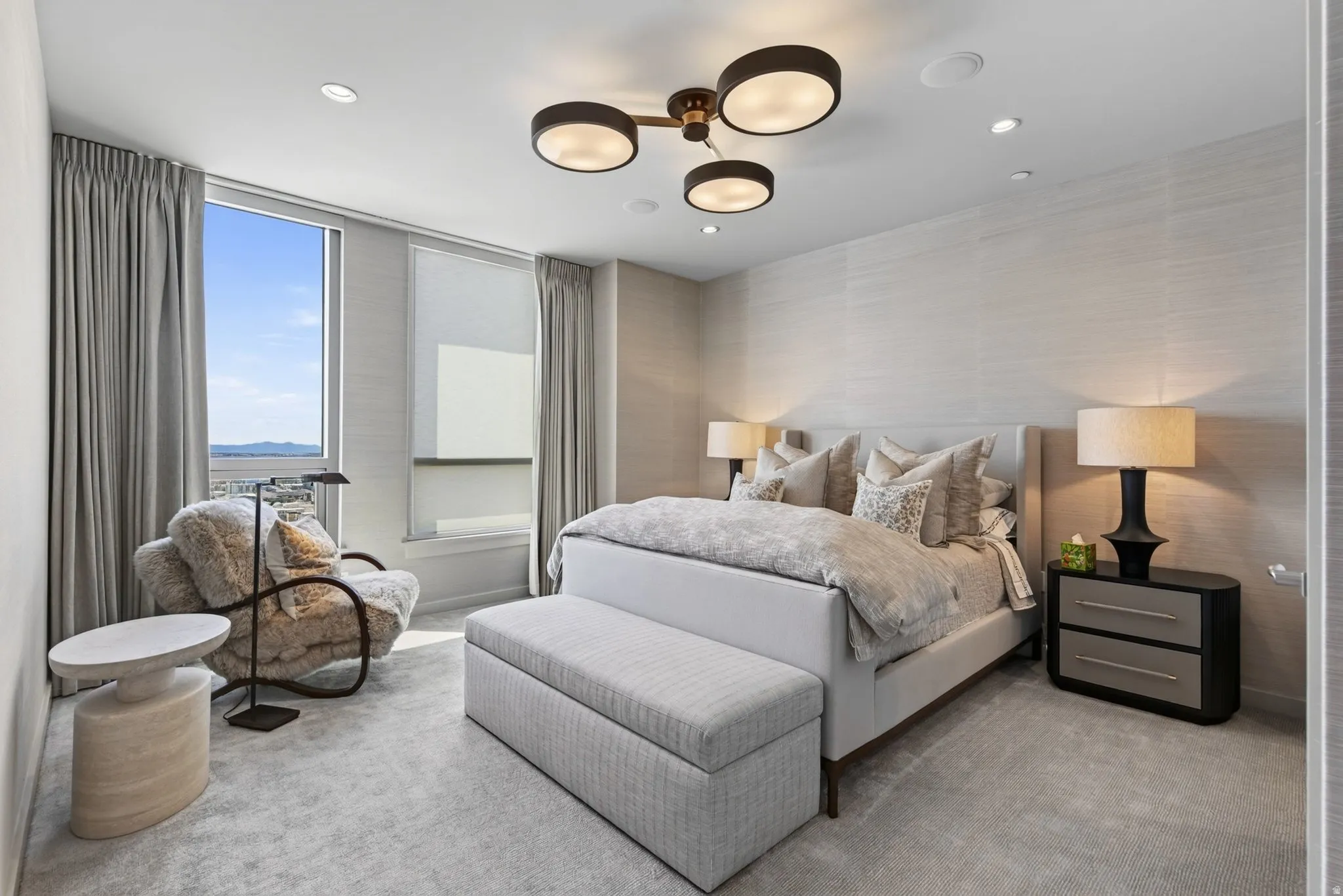Light-filled room featuring expansive windows with roller shades and drapery