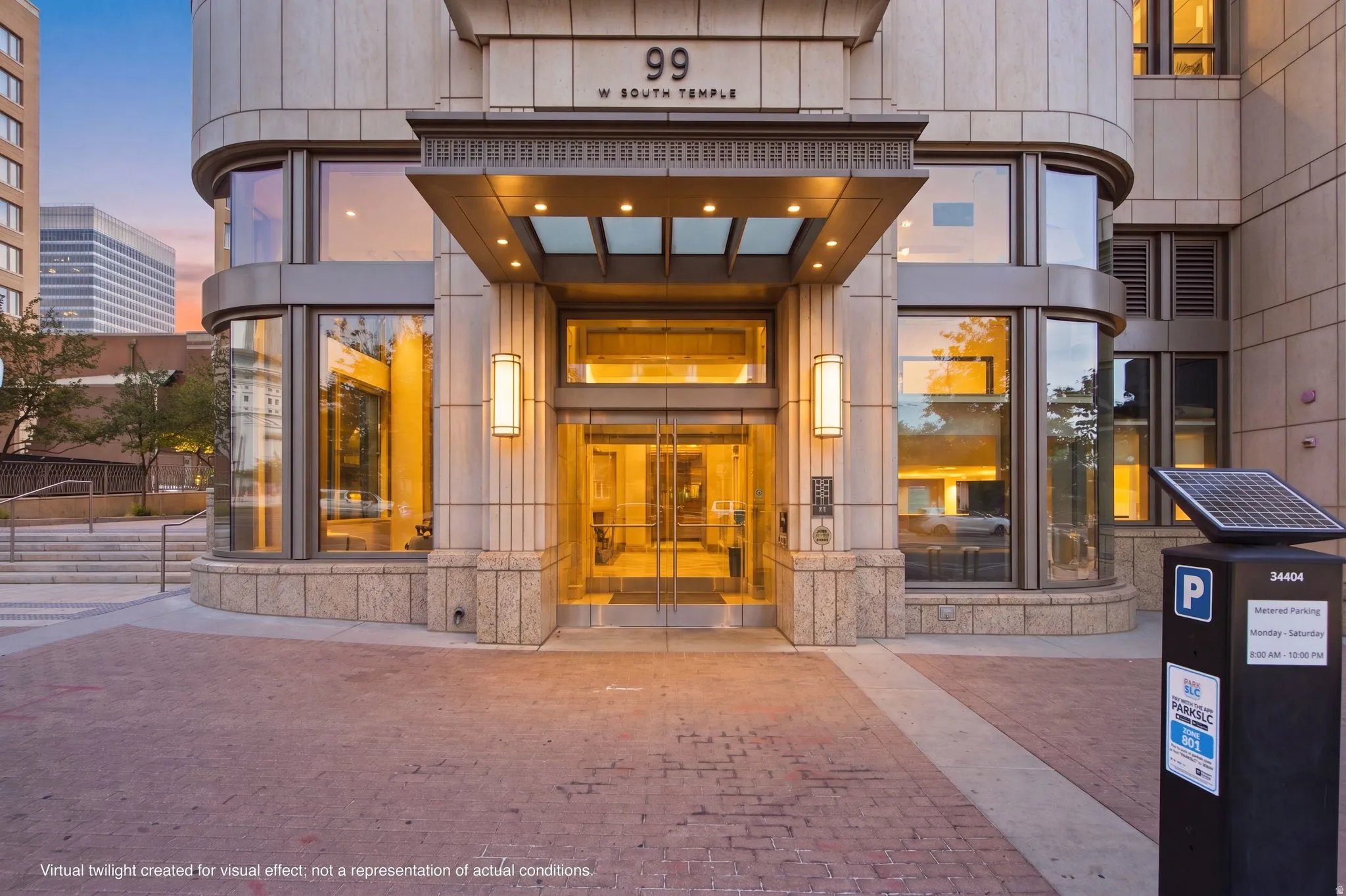 Modern building entrance featuring a glass canopy, double glass doors, and stone facade