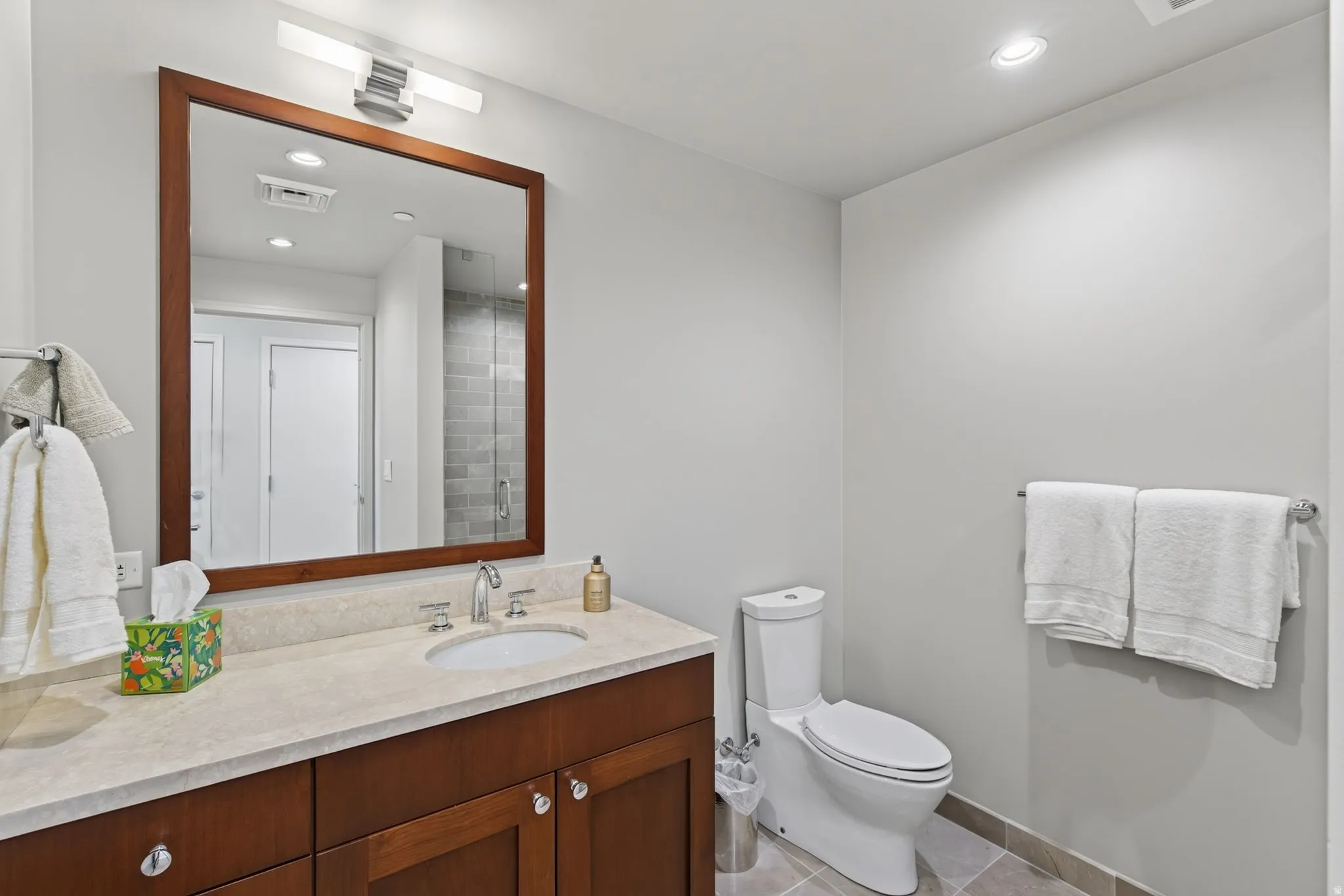 Bathroom vanity featuring a wood-framed mirror, undermount sink, and polished chrome fixtures
