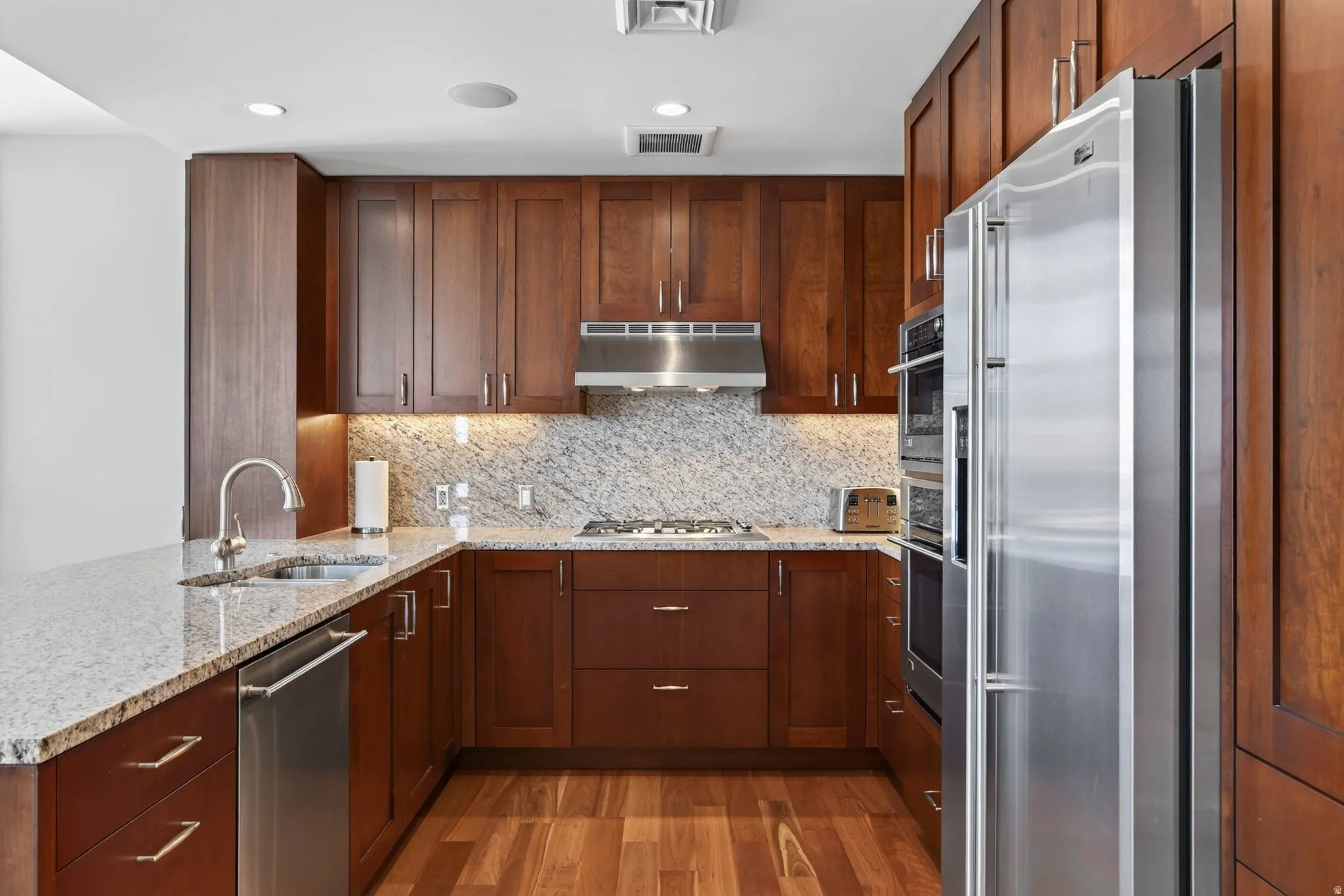 U-shaped kitchen with wood cabinetry and stainless steel appliances