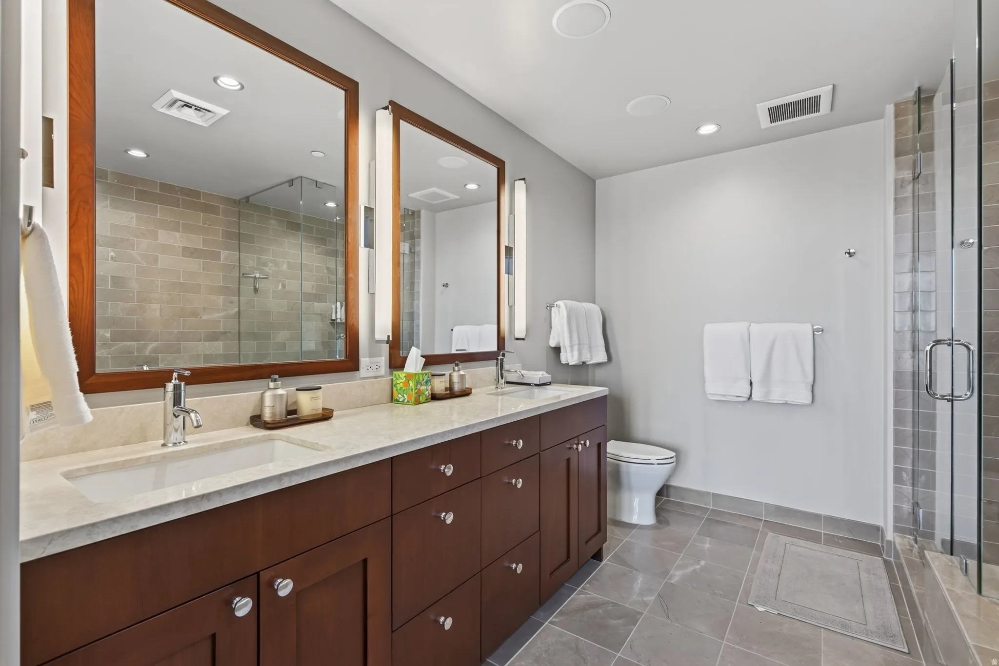 Dual vanity with a light-colored countertop, under-mount sinks, and wood-framed mirrors
