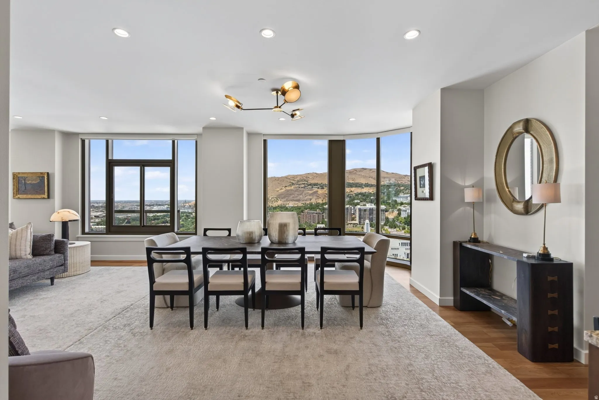Open-concept living and dining area featuring expansive windows, a contemporary chandelier, recessed lighting, hardwood flooring, and neutral wall tones