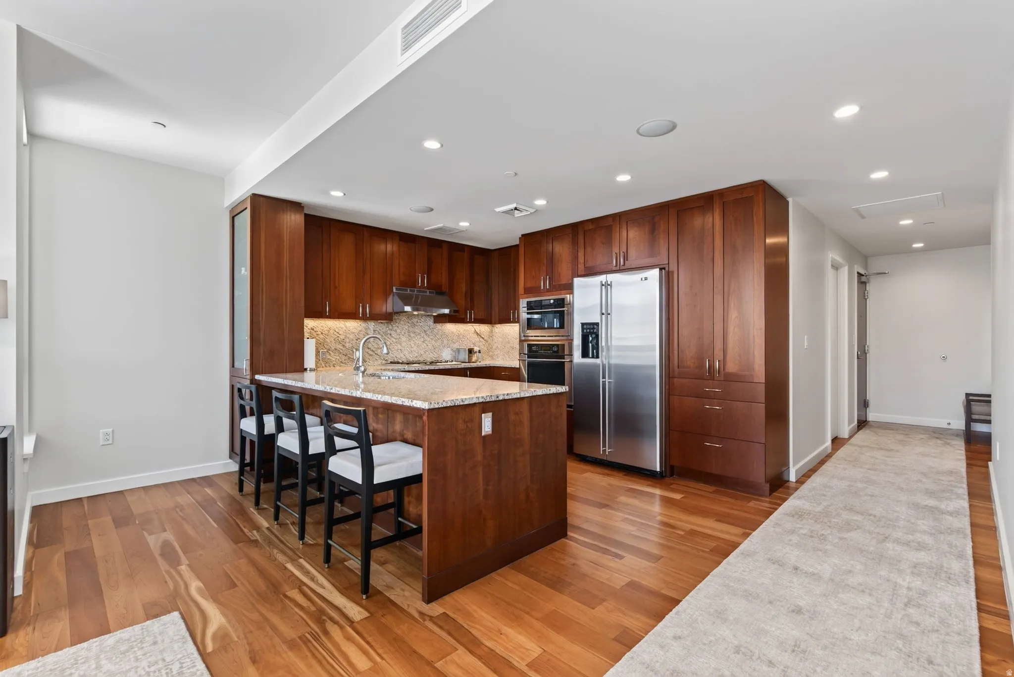 Kitchen featuring rich wood cabinetry, stainless steel appliances, and a central island with a light-toned countertop