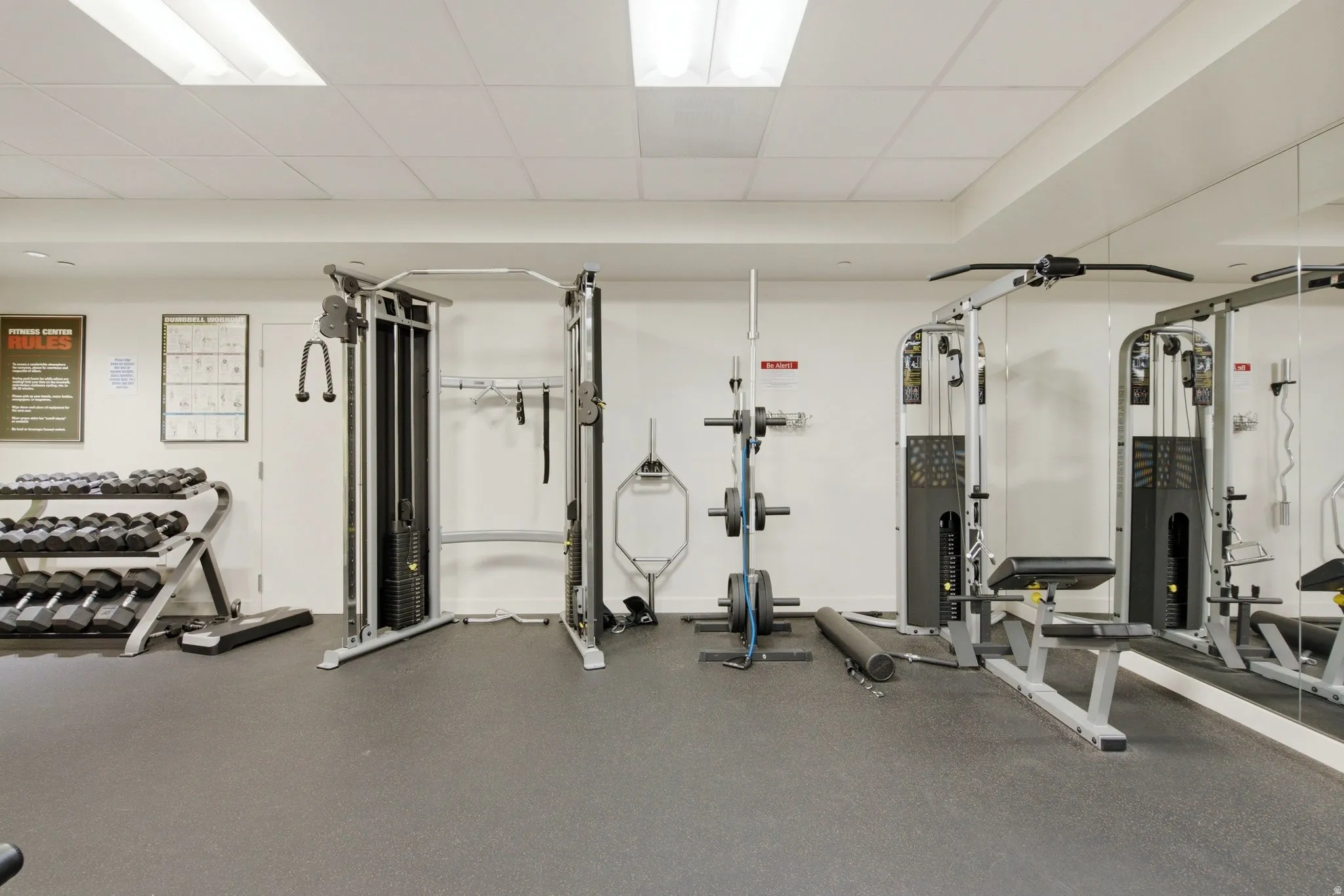 Dedicated fitness center featuring weight training equipment, mirrored walls, and resilient flooring