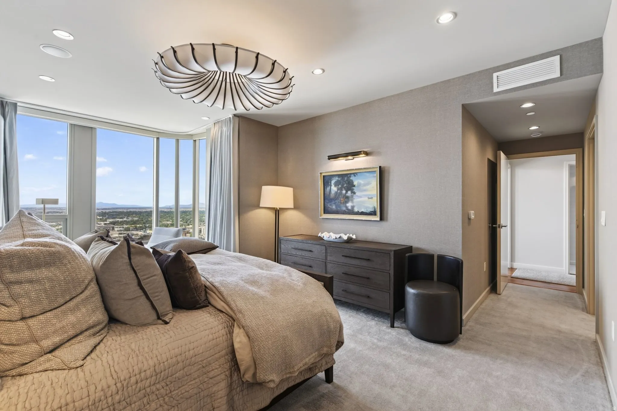 Curved floor-to-ceiling windows with expansive scenery, recessed ceiling lighting, textured wall finishes, a distinctive ceiling fixture, and light-toned carpeting
