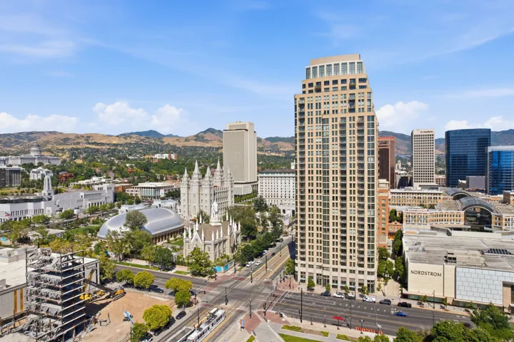 Urban skyline featuring a prominent residential tower with multiple balconies, alongside commercial buildings and historic structures