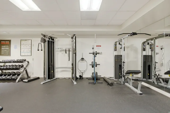 Dedicated fitness center featuring weight training equipment, mirrored walls, and resilient flooring