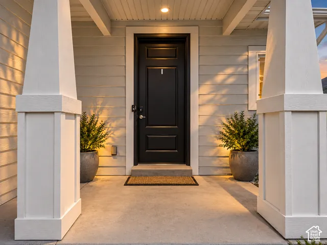 Covered entry with concrete flooring and substantial white columns
