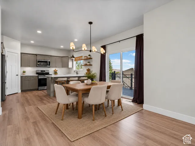 Wood-finish flooring throughout, kitchen with shaker cabinetry and stainless steel appliances, white subway tile backsplash, and a sliding glass door